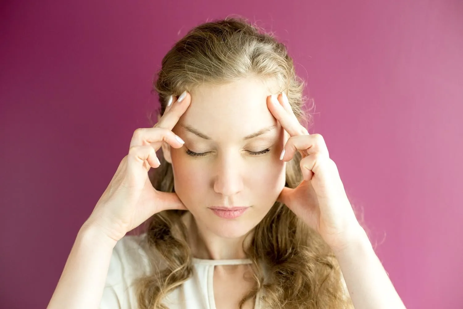 A woman with her eyes closed, fingers resting at her temples
