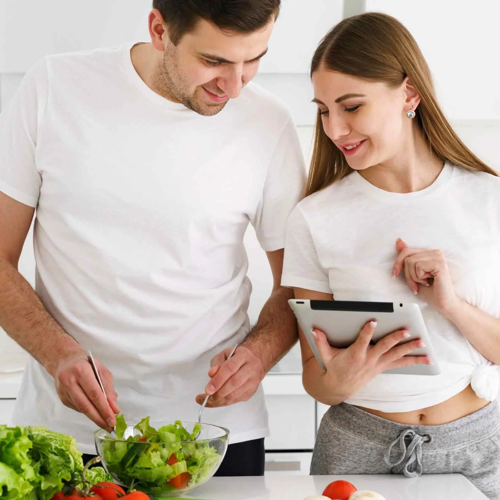 Two people putting a fresh salad together in the kitchen